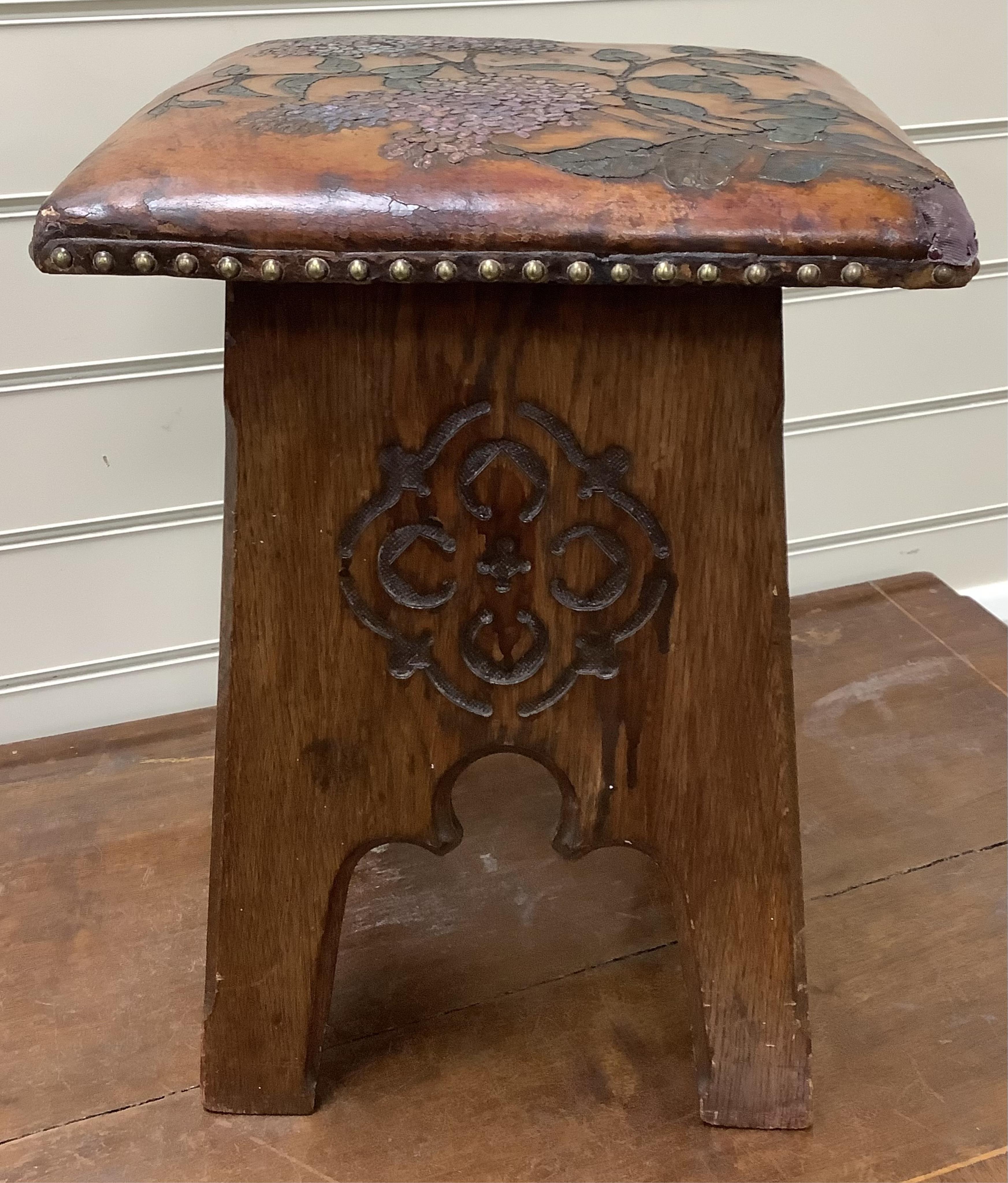 An early 20th century Liberty & Co. Arts & Crafts style stool with embossed leather seat, (later coloured), width 31cm, height 42cm. Condition - fair